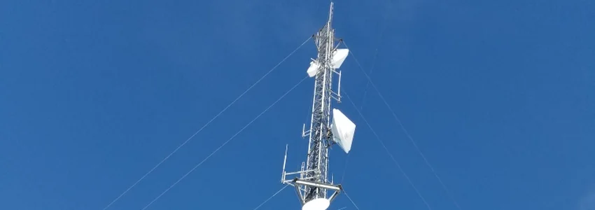 Guyed communications tower with microwave dishes and panel antennas